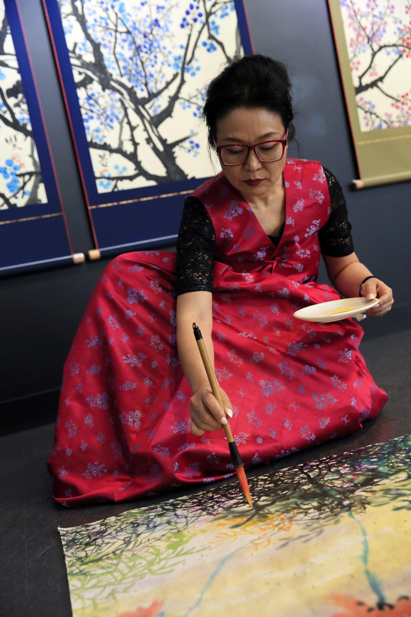 artiste peintre Choé Joo-Young peignant assise en tenue traditionnelle coréenne avec le pinceau en poils de chèvre